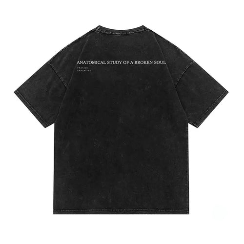 A black mineral-wash short-sleeve t-shirt shown from the back, featuring the text 'ANATOMICAL STUDY OF A BROKEN SOUL' and 'FATAL ATTRACTION' printed in white across the upper back.