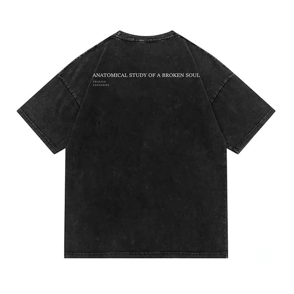 A black mineral-wash short-sleeve t-shirt shown from the back, featuring the text 'ANATOMICAL STUDY OF A BROKEN SOUL' and 'FATAL ATTRACTION' printed in white across the upper back.