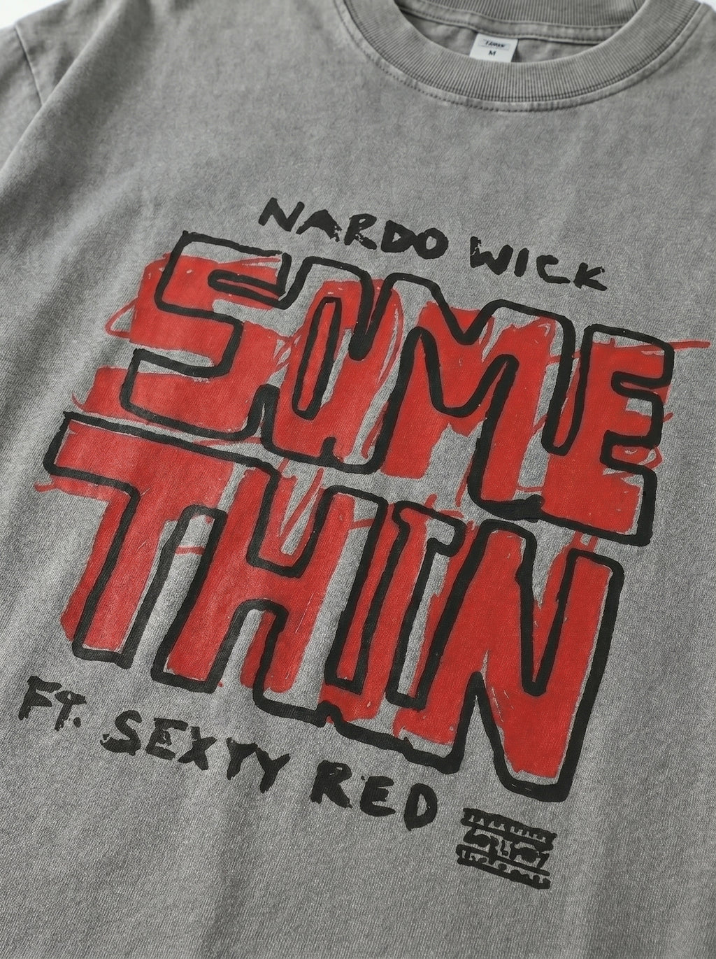 Gray t-shirt with red and black text design on a plain background
