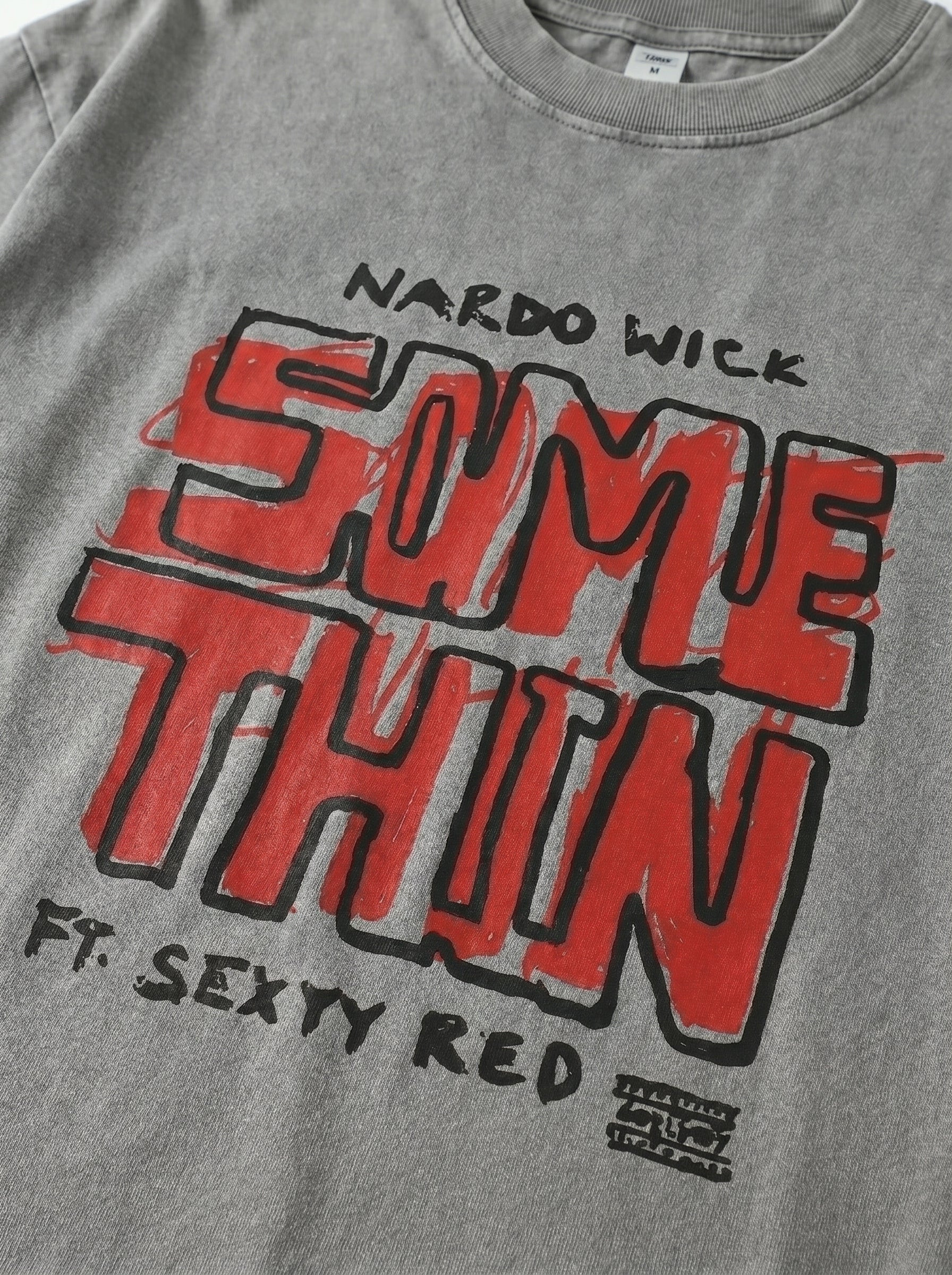 Gray t-shirt with red and black text design on a plain background
